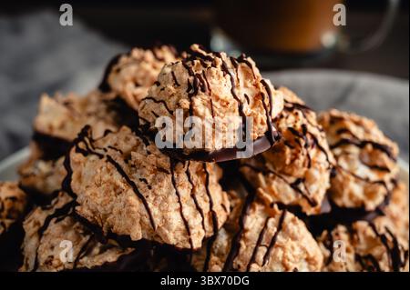 Close-up of a Pile of Macaroons Drizzled in Dark Chocolate: Plate of toasted coconut meringue drop cookies dipped in bittersweet chocolate close-up Stock Photo