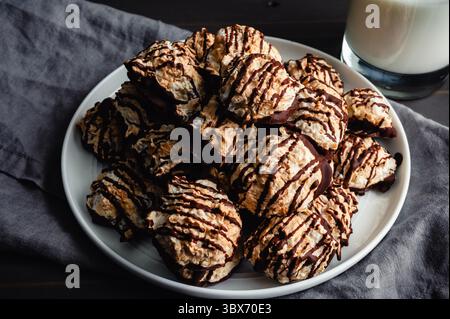 Close-up of a Pile of Macaroons Drizzled in Dark Chocolate: Plate of toasted coconut meringue drop cookies dipped in bittersweet chocolate close-up Stock Photo