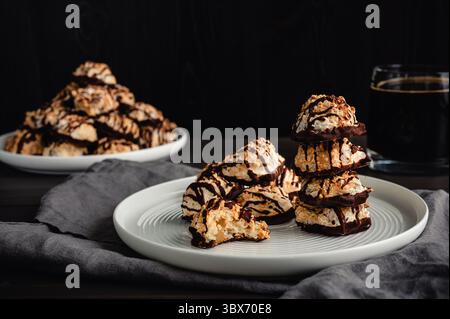 Macaroons Drizzled with Dark Chocolate on a Small Plate: Toasted coconut meringue drop cookies dipped in bittersweet chocolate close-up Stock Photo