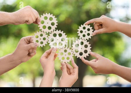 Many hands with wooden gears in park Stock Photo