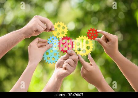 Many hands with colorful gears in park Stock Photo