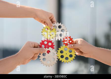 Many hands with gears outdoors Stock Photo