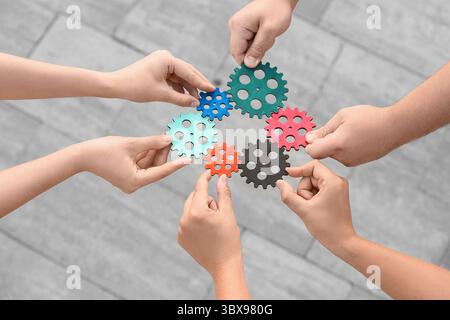 Many hands with gears outdoors Stock Photo