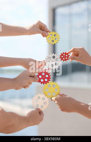 Many hands with gears outdoors Stock Photo