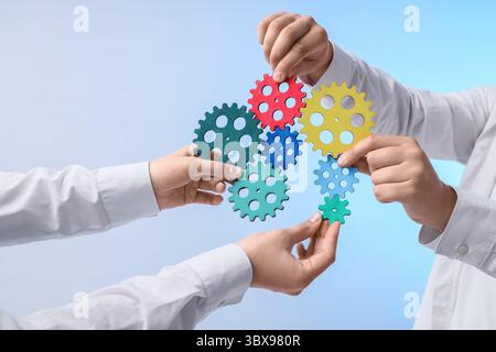 Female hands with colorful gears on light background Stock Photo