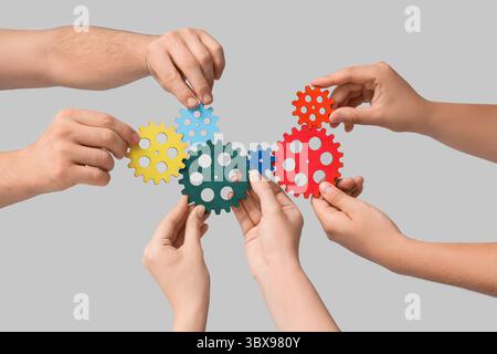Many hands with colorful gears on light background Stock Photo