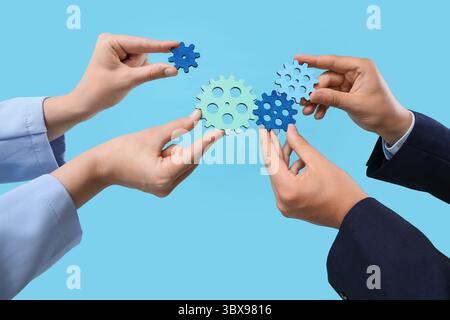 Hands with gears on blue background Stock Photo
