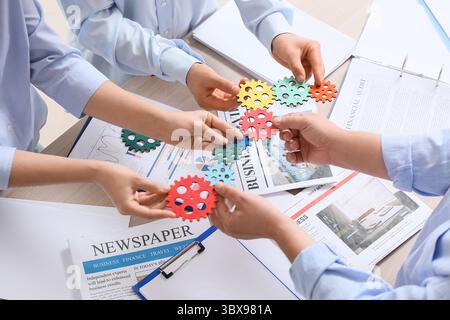 Engineers with colorful gears at table in office, closeup Stock Photo