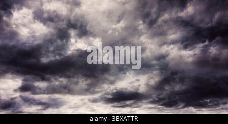 Dense dark grey clouds are being shown in open sky flat design, featuring layered storm patterns Stock Photo