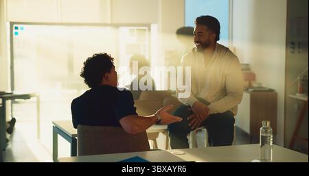 University, student and men in classroom, discussion and preparing for exam, lens flare and talking. Happy, people and conversation with classmate in Stock Photo