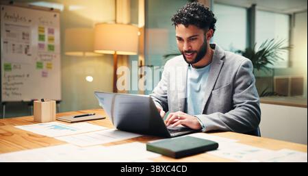 Businessman, financial analyst or typing with laptop at night for company report in office. Man, accountant or finance advisor working late with Stock Photo