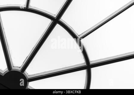 Black and white photo of a geometric window detail featuring intersecting lines and shapes, creating an abstract composition Stock Photo