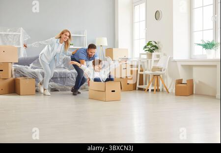 Happy family, cheerful owners cardboard boxes playing moving new flat, enter home, excited parents Stock Photo