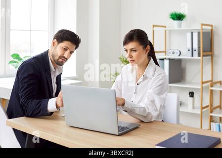 Two business people having meeting, looking at laptop monitor screen and analyzing financial data. Stock Photo