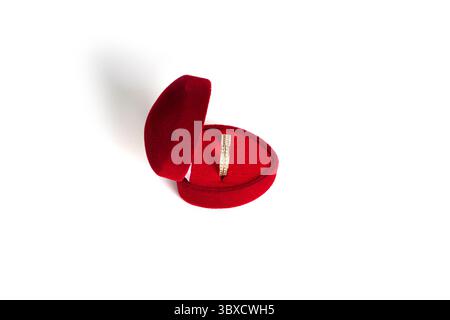 Golden wedding ring in a red heart-shaped jewelry box isolated on a white background. High quality photo Stock Photo
