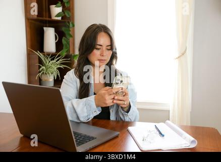 Woman working from home on phone with pop socket Stock Photo