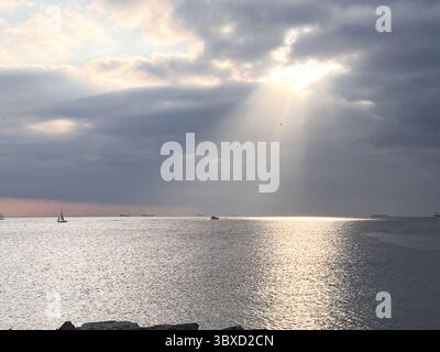 Sunset over the sea with light rays coming through the clouds. Stock Photo