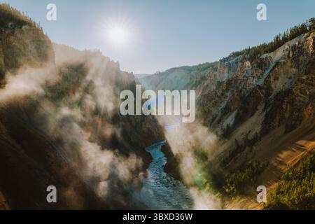 Sunlight breaks through clouds over mist-filled canyon walls Stock Photo