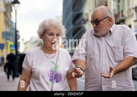 Moscow, Russia - July 16, 2025: Old couple talking emotionally on city street in summer Stock Photo