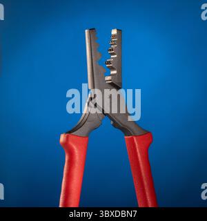 This image features specialized crimping pliers designed for crimping the ends of electrical cables, elegantly displayed against a smooth blue gradien Stock Photo