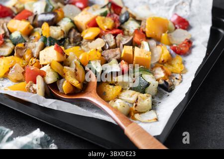 Roasted vegetables on a baking tray on black background Stock Photo