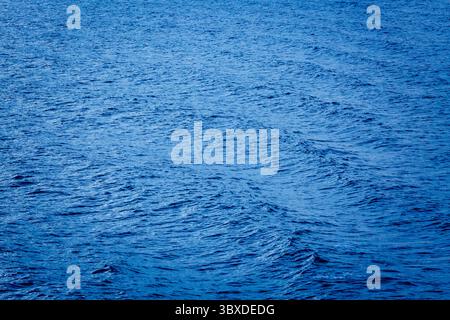 Sunlight on the surface of the sea, windblown effect and ripples radiating out. Stock Photo