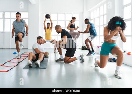 Multiethnic group of sportive people doing functional workout in training class gym group of multi-ethnic athletes exercising with a personal trainer Stock Photo