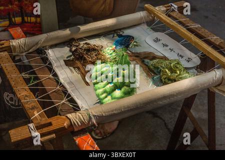 May 27, 2013, Guilin, Guangxi Region, China: An elaborate needlework wallhanging of a peacock being hand-stitched in Guilin, China. (Credit Image: © Jon G. Fuller/VW Pics via ZUMA Press Wire) Stock Photo