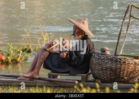 May 28, 2014, Xing Ping, Shaanxi Province, China: Elderly traditional cormorant fisherman smokes a wooden pipe on his raft on the Li River, Xingping, China. (Credit Image: © Jon G. Fuller/VW Pics via ZUMA Press Wire) Stock Photo