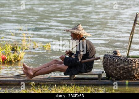 May 28, 2014, Xing Ping, Shaanxi Province, China: Elderly traditional cormorant fisherman smokes a wooden pipe on his raft on the Li River, Xingping, China. (Credit Image: © Jon G. Fuller/VW Pics via ZUMA Press Wire) Stock Photo