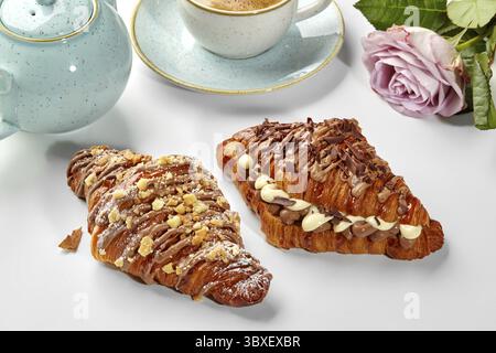 Two freshly baked croissants filled with chocolate, accompanied by a cup of coffee, create a tempting breakfast setting Stock Photo