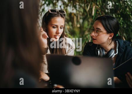 High school friends discussing study assignments in cozy coffee shop Stock Photo