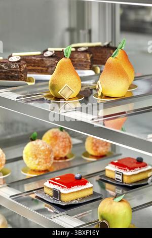 Various fresh baked sweet cakes and fruit shaped pastries presented on showcase in confectionery. Sweet tooth concept Stock Photo