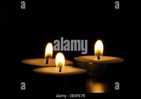 Three candles shining in the dark with customizable space for message, text or ideas. Copy space and candles concept Stock Photo