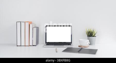 A minimalist workspace featuring a laptop with a blank screen, books, and a plant on a desk, promoting productivity Stock Photo