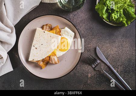 Food, Quesadilla with fried egg, bacon and cheese on a plate on the table top view Stock Photo