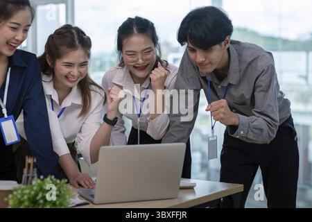 A diverse business team celebrates success and analyzes achievements together in a modern office setting, showcasing teamwork and collaboration Stock Photo