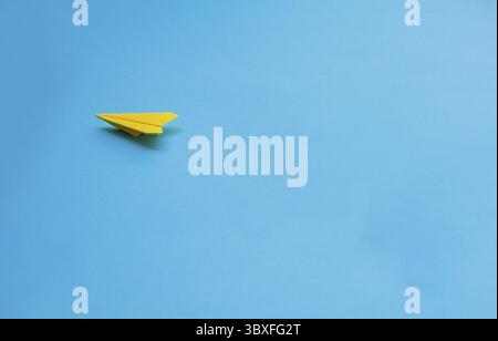 Yellow paper airplane on blue background Stock Photo