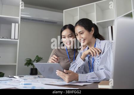 Two Asian women collaborating on a project in a modern office. Concept of teamwork, collaboration, and productivity Stock Photo