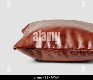 Artisanal plump sofa pillow of smooth copper colored leather on white background, closeup side view. Stylish accessory for comfortable interior design Stock Photo