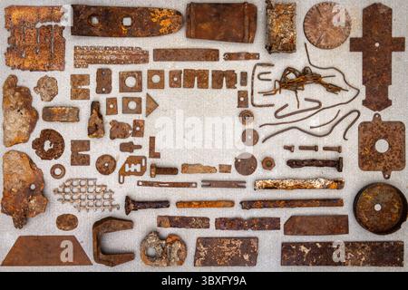 A group of various old rusty bits and pieces arranged on a concrete surface. Old rusty nuts, bolts, nails and other parts flay lay on gray background. Stock Photo