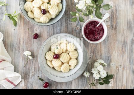 Food, Traditional Ukrainian lazy cottage cheese dumplings served with sour cream and cherry sauce and fresh cherries on a wooden background Stock Photo
