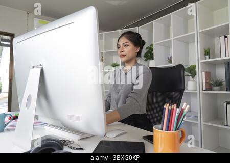 A professional graphic designer focused on work at a computer in a modern office with creative workspace and stylish decor Stock Photo