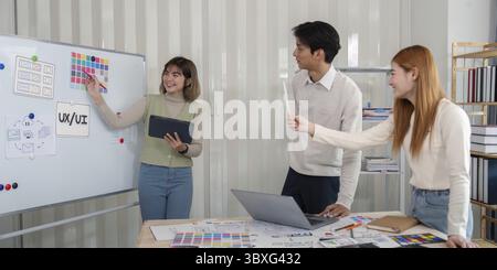 Team of UX developers and UI designers collaborating on a project, brainstorming ideas, and discussing design concepts in a modern office setting Stock Photo