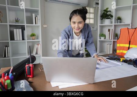 An engineer analyzes project data on a laptop, focusing on construction planning and effective project management in the office Stock Photo