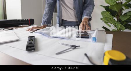 An architect conducts detailed cost calculations for accurate blueprint planning, ensuring budget management and successful execution of architectural Stock Photo