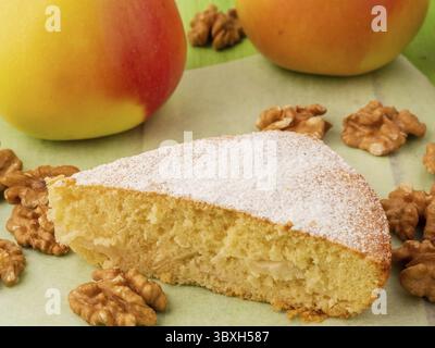 A piece of Charlotte on parchment, nuts and apples. Apple pie biscuit dough decorated with icing sugar Stock Photo