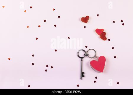 Key in shape of heart with confetti on keychain on pink background. Valentine's day romantic concept. Top view, flat lay, copy space. Selective focus Stock Photo