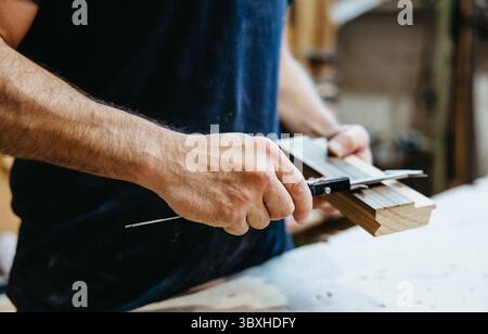 Man using caliper to measure wood in carpentry workshop, close-up Stock Photo