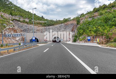 A modern highway approaches the entrance of a road tunnel Stock Photo